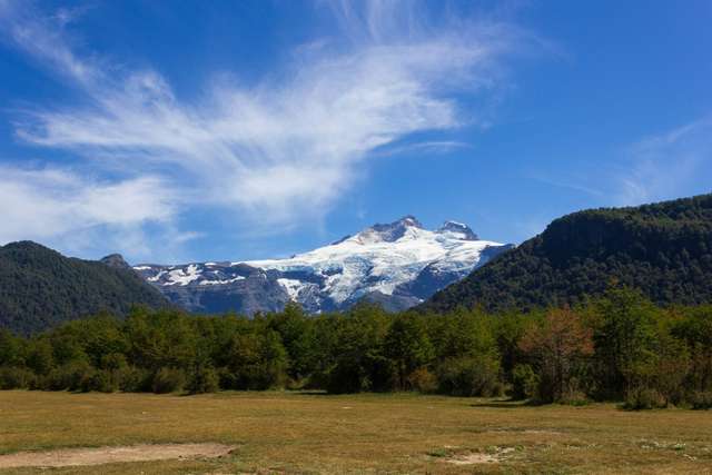 Bariloche. Gramado com arvores verdes e montanhas ao fundo durante o dia.