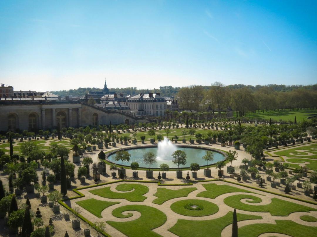 Foto-dos-jardins-do-Palacio de Versalhes. Campo de grama verde com fonte no meio