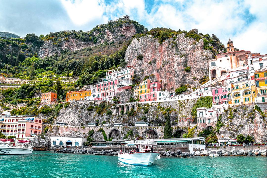 Foto Amalfi, Itália. Com mar azul, barcos e casas coloridas na encosta.