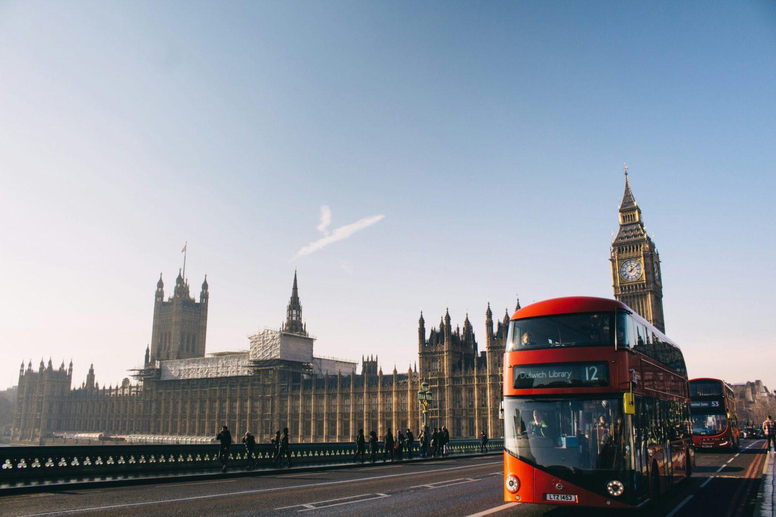 Foto da casa do parlamento em Londres com Big Ben e onibus vermelho de dois andares